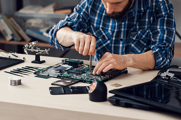 Laptop disassembling with screwdriver at repair shop. Engineer fixing broken computer motherboard. Electronic renovation, technology development concept